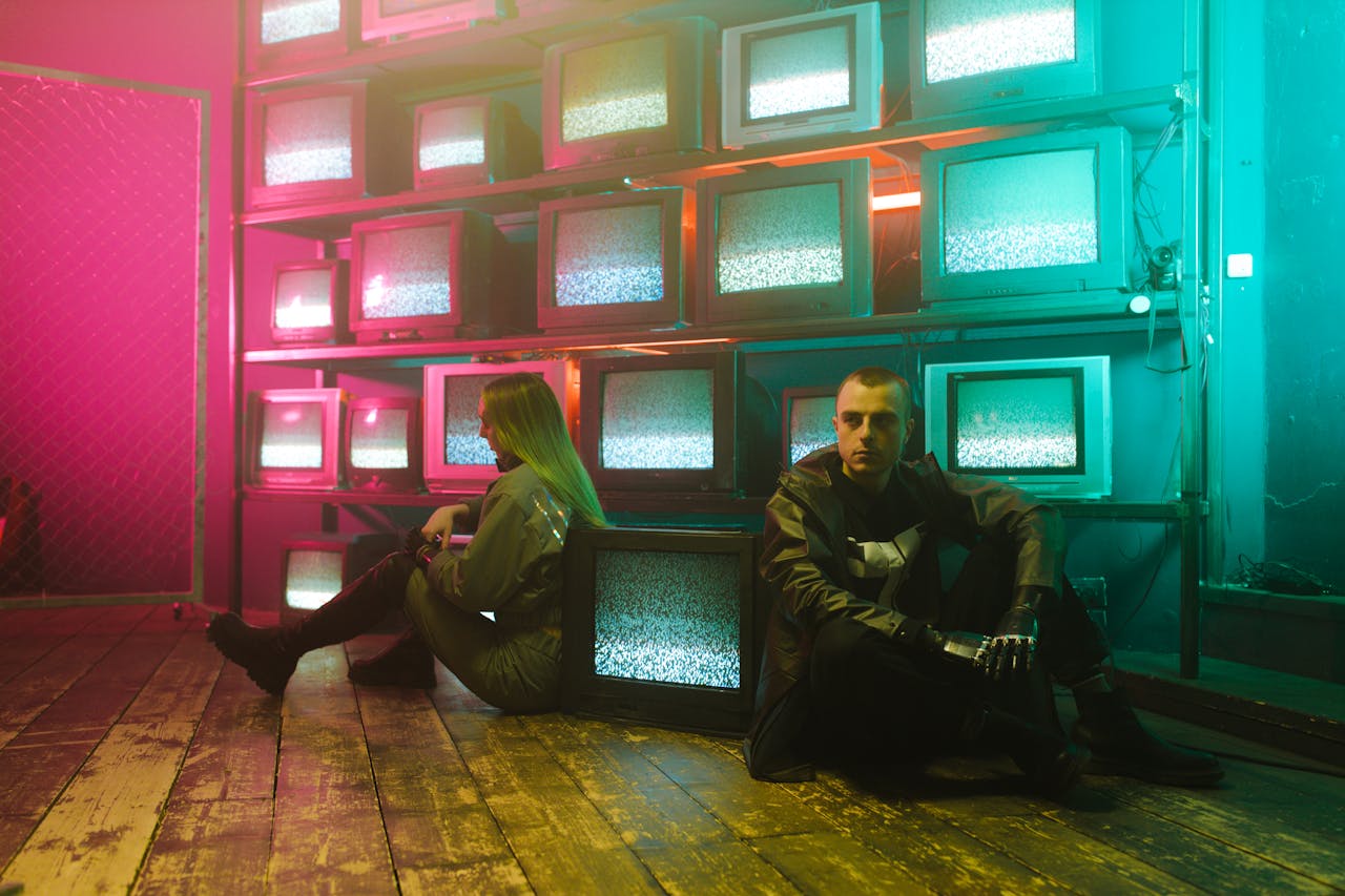 Two individuals in a cyberpunk setting with neon lighting and stacked television screens.